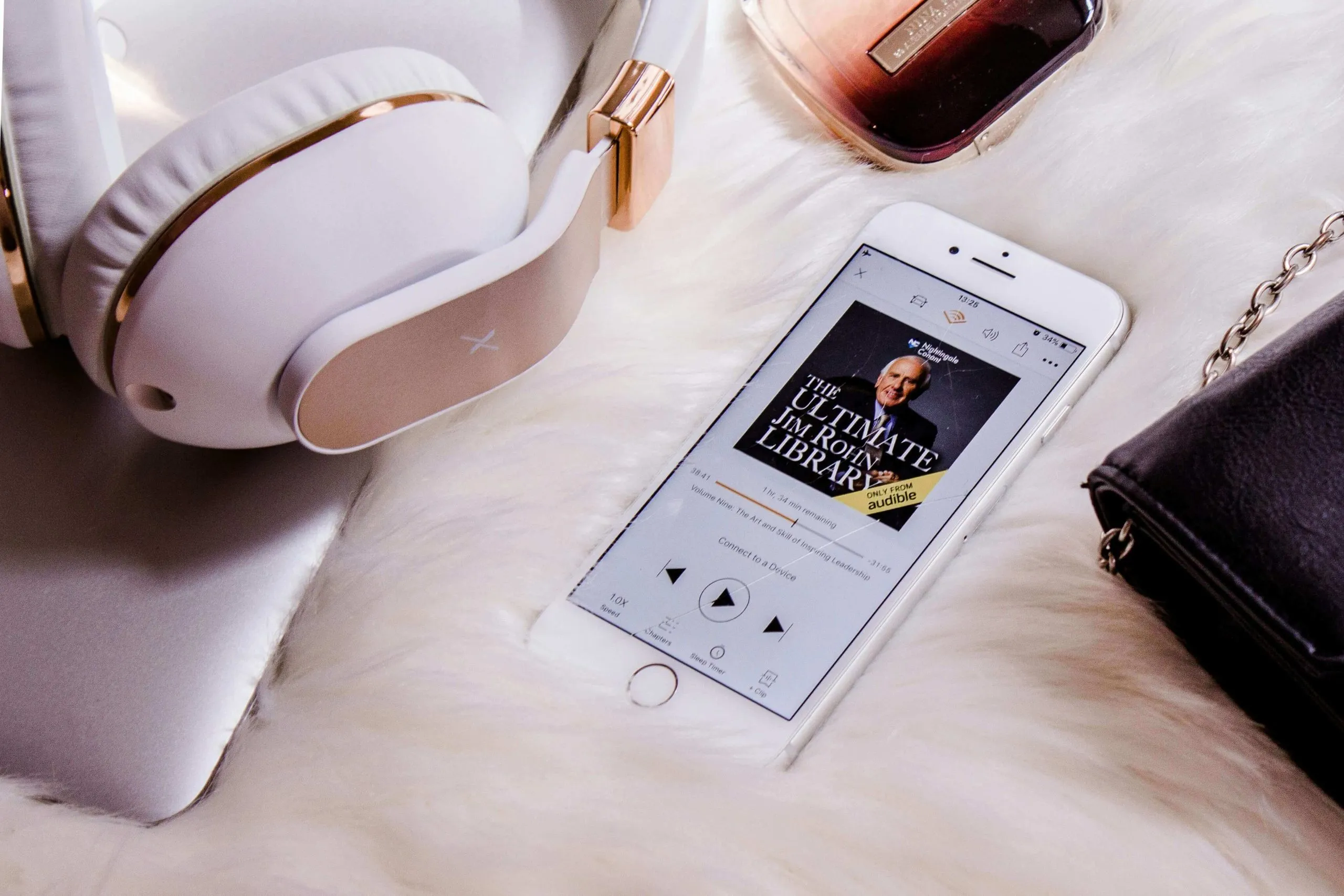 A smartphone with an audiobook playing on it next to headphones